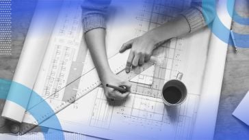 An architect works on plans with a square and triangle with a cup of coffee