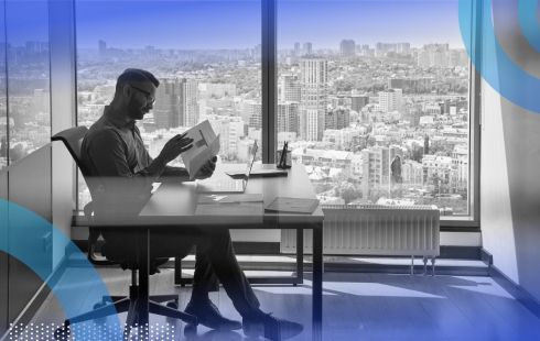 A person sits at a desk reviewing a book of regulations.