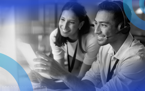 Two tech team members are smiling and looking at a computer screen.